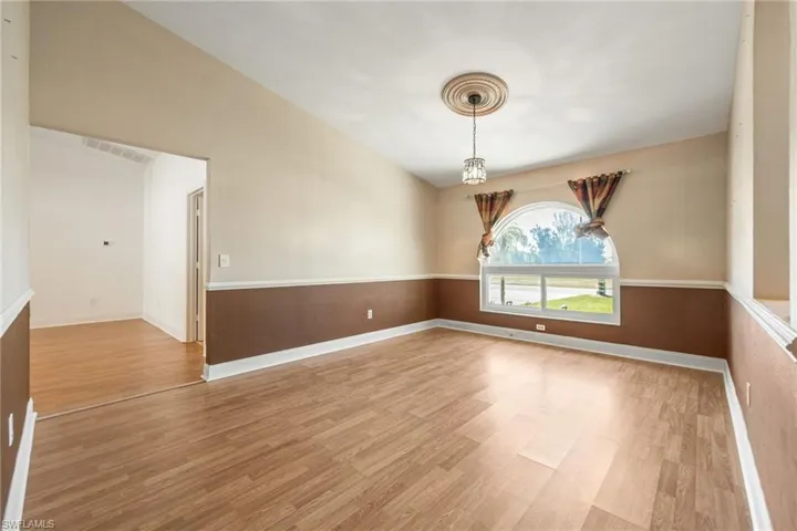 Empty room featuring a chandelier, light wood finished floors, visible vents, and baseboards