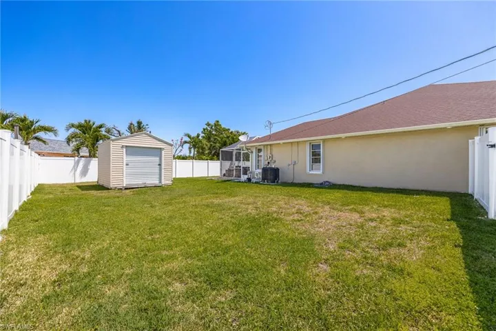 View of yard featuring an outbuilding, a fenced backyard, central AC unit, and a storage unit