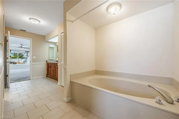 Full bathroom featuring vanity, baseboards, tile patterned floors, a ceiling fan, and a bath