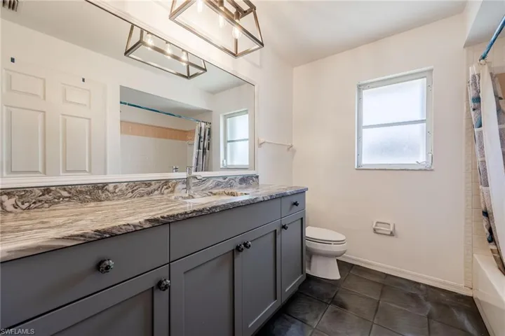 Full bath with vanity, baseboards, tile patterned floors, toilet, and visible vents