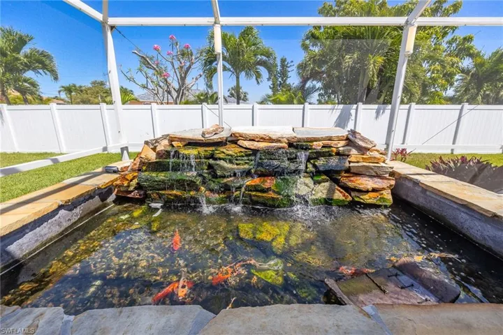 View of swimming pool with a fenced backyard and a garden pond