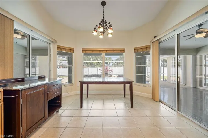 Dining area featuring baseboards, light tile patterned flooring, and ceiling fan with notable chandelier