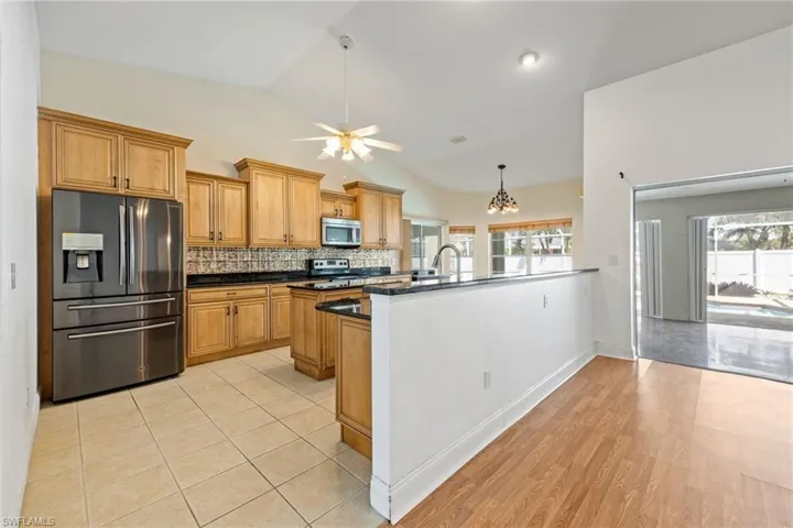 Kitchen with tasteful backsplash, a peninsula, appliances with stainless steel finishes, a healthy amount of sunlight, and dark countertops