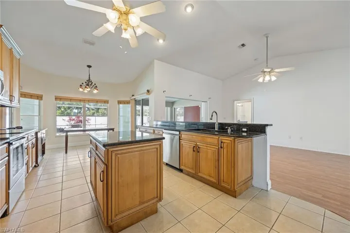 Kitchen with ceiling fan with notable chandelier, visible vents, a kitchen island, appliances with stainless steel finishes, and a sink