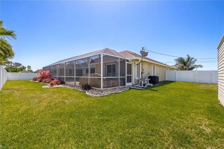 Rear view of property with a fenced backyard, cooling unit, and a lawn