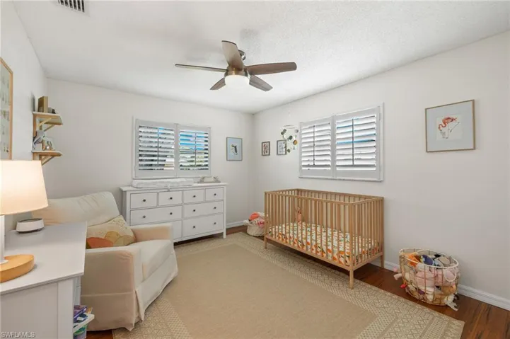 Bedroom with a crib, ceiling fan, and hardwood / wood-style floors