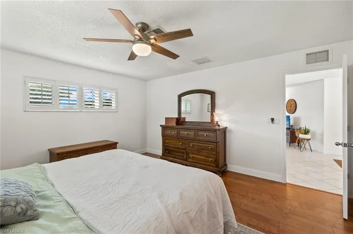 Bedroom with ceiling fan, a textured ceiling, and light tile floors