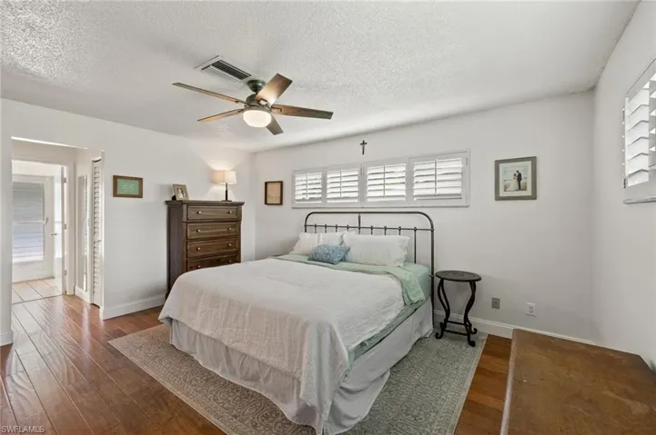 Bedroom featuring a textured ceiling, ceiling fan, ensuite bath, and dark hardwood / wood-style flooring