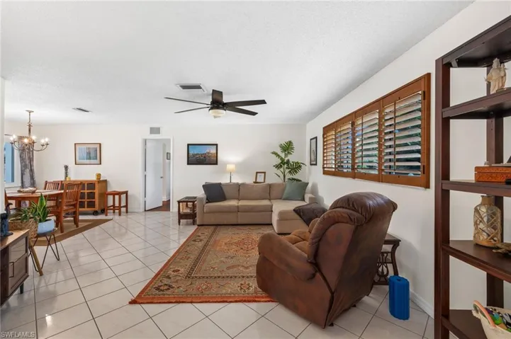 Living room featuring ceiling fan with notable chandelier, a textured ceiling, and light tile flooring