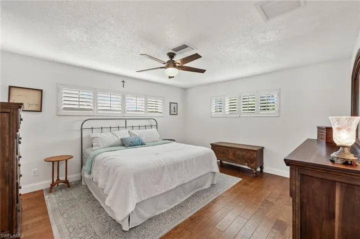 Bedroom featuring a textured ceiling, dark wood-type flooring, and ceiling fan