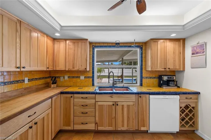 Kitchen featuring backsplash, sink, ceiling fan, and white dishwasher
