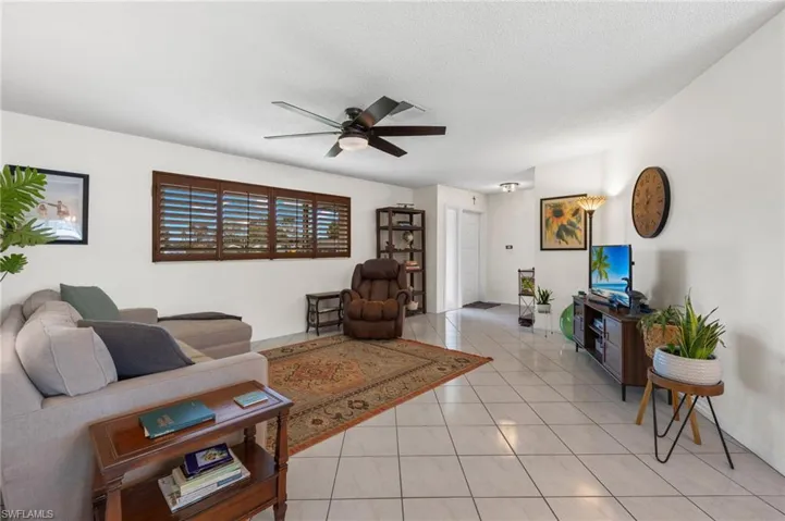 Living room featuring a textured ceiling, ceiling fan, and light tile floors