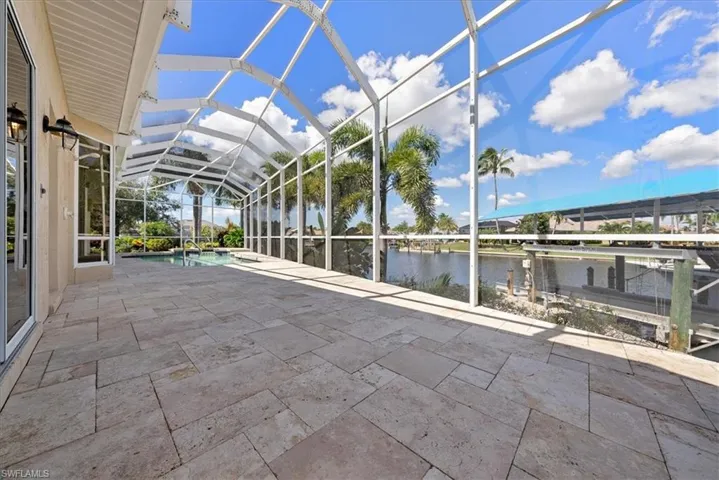 Unfurnished lanai with vaulted ceiling, a patio, and a water view