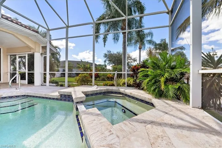 View of swimming pool featuring a sunroom, a pool with connected hot tub, a patio and waterview