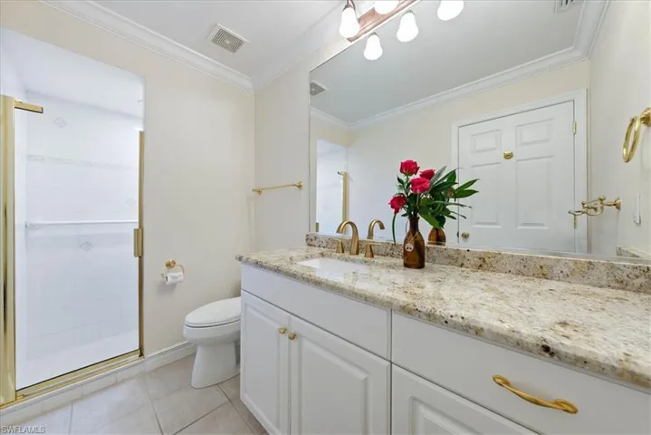 Full bathroom with crown molding, vanity, light tile patterned flooring, and a shower stall