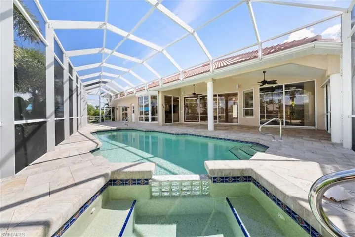 View of swimming pool featuring a sunroom, a pool with connected hot tub, a patio and waterview