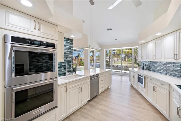 Newer Kitchen featuring tasteful backsplash, appliances with stainless steel (Kitchen Aid Appliances) a ceiling fan, recessed lighting, and quarts counters