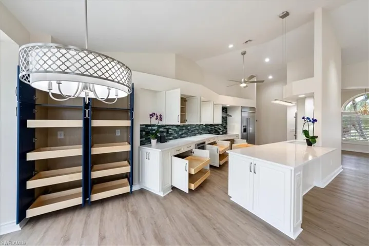 Newer Kitchen featuring tasteful backsplash, lLux vinyl flooring, wall chimney range hood, and ceiling fan, Wood pull outs everywhere!
