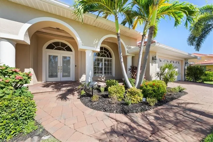 View of exterior entry with a garage, stucco siding, driveway, and french doors