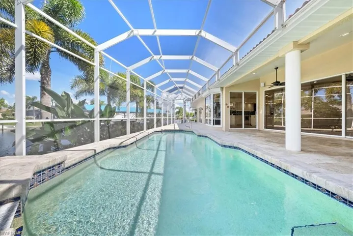 View of swimming pool featuring a sunroom, a pool with connected hot tub, a patio and waterview