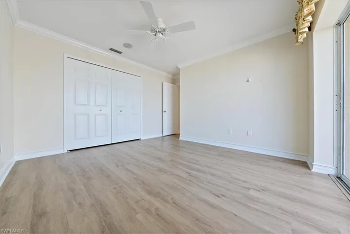Unfurnished bedroom featuring crown molding, light wood-type flooring, a closet, and a ceiling fan