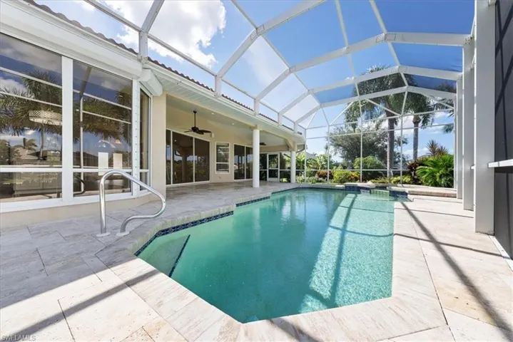 View of swimming pool featuring a sunroom, a pool with connected hot tub, a patio and waterview