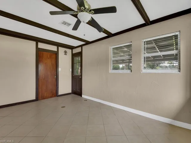 Tiled empty room with beam ceiling and ceiling fan