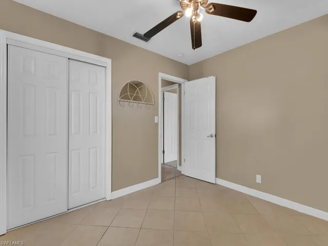 Unfurnished bedroom featuring light tile patterned flooring, ceiling fan, and a closet