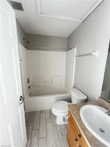 Bathroom with vanity, shower / bathtub combination, and wood finish floors