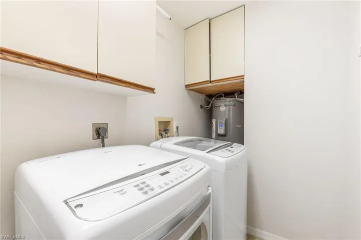 In-house Laundry area with cabinets, separate washer and dryer, and electric water heater