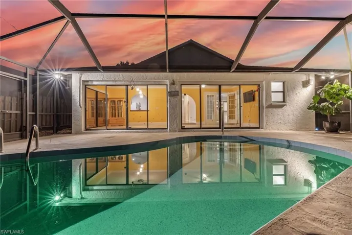 Pool at twilight featuring a patio area, and screened lanai