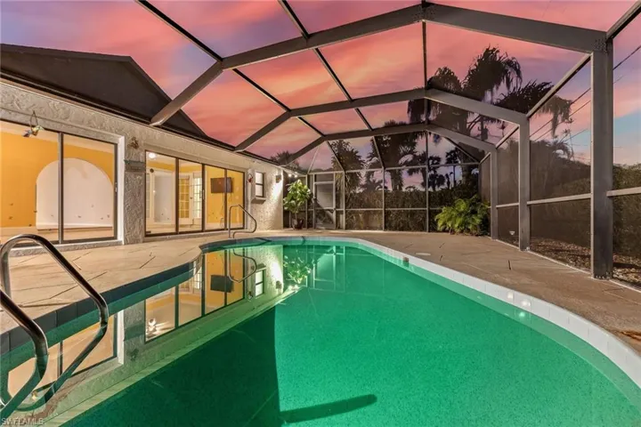 Pool at twilight featuring a patio area, and screened lanai