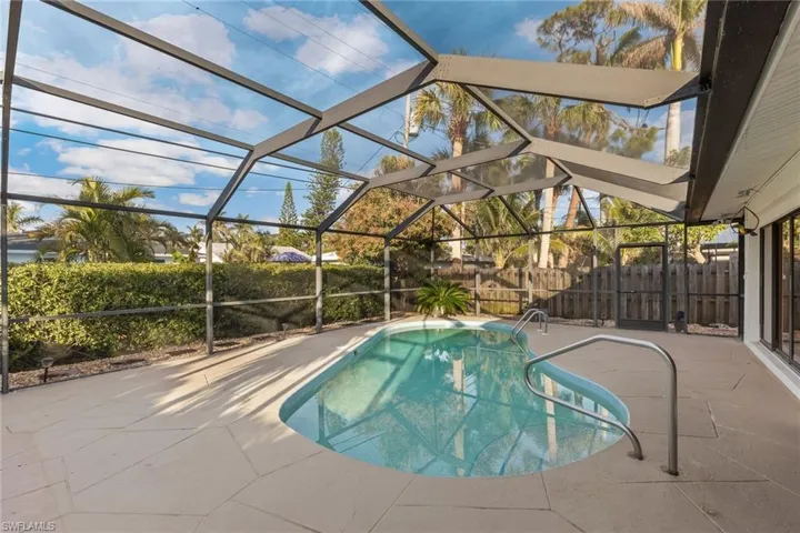 View of pool featuring a patio area and glass enclosure