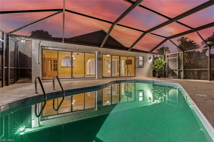Pool at twilight featuring a patio area, and screened lanai