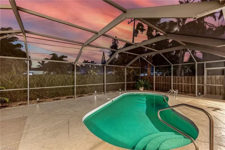Pool at twilight featuring a patio area, and screened lanai