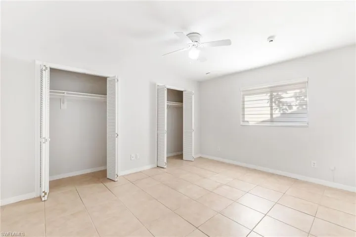 Guest bedroom with multiple closets, ceiling fan, and light tile patterned floors