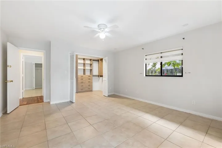 Master bedroom featuring tiled floors, ensuite bath, and large walk-in closet with built-in system