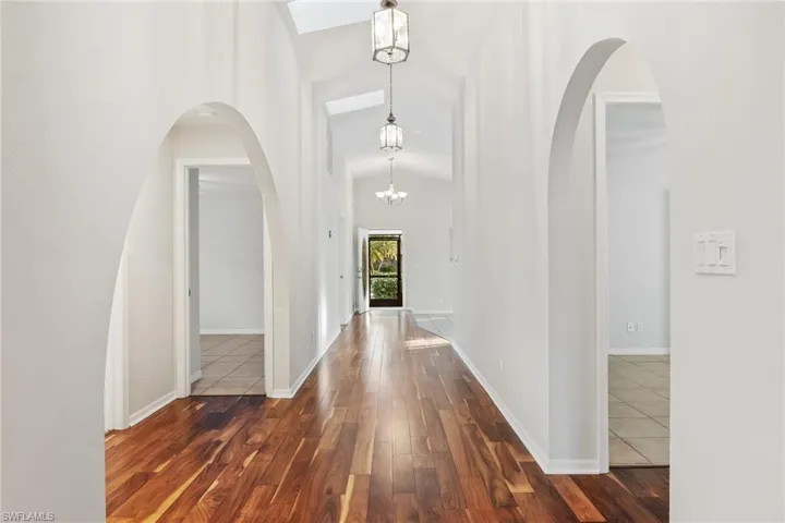 Foyer entrance/hallway featuring wood flooring, an inviting chandelier, and vaulted ceiling