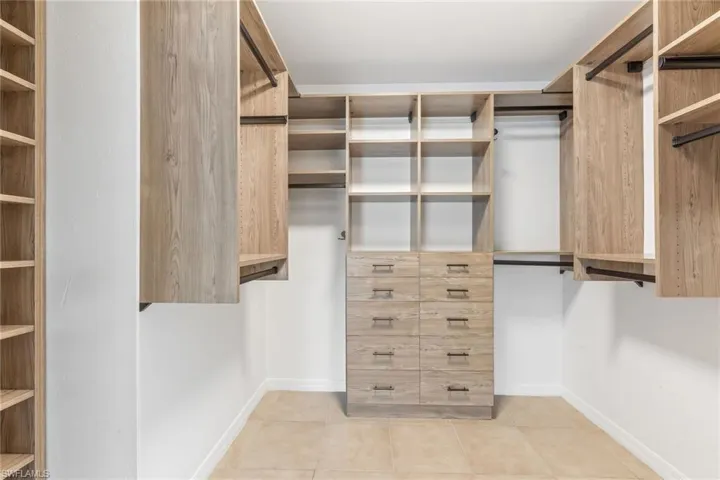 Large walk-in closet featuring light tile patterned floors, and built-in closet organizer
