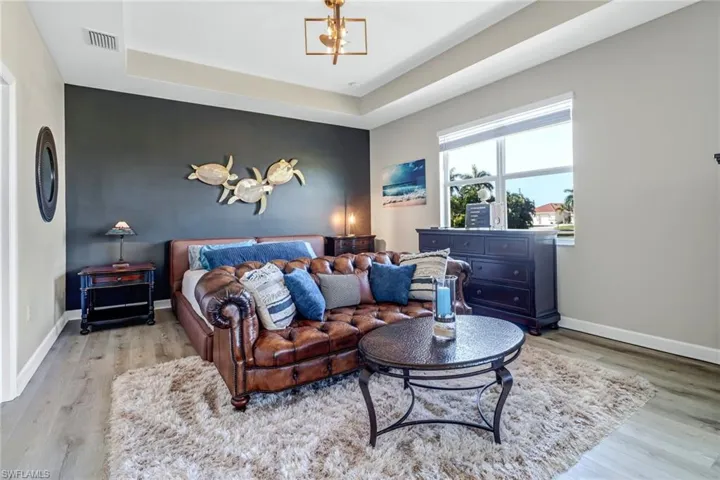 Bedroom with a notable chandelier, light wood-type flooring, and a tray ceiling