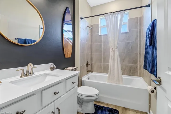 Full bathroom featuring vanity, toilet, hardwood / wood-style floors, and shower / bath combination with curtain
