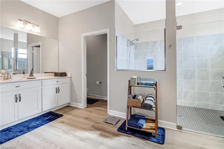 Bathroom with vanity, tiled shower, and hardwood / wood-style floors