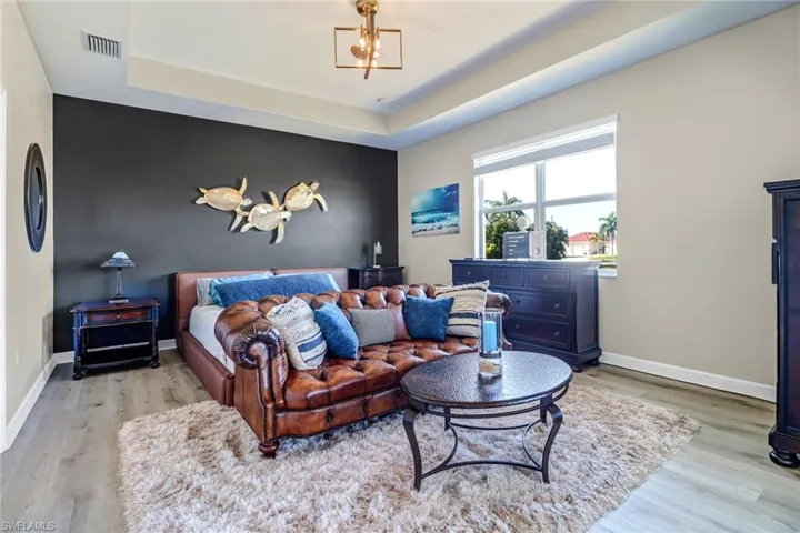 Bedroom featuring light hardwood / wood-style floors, a notable chandelier, and a raised ceiling