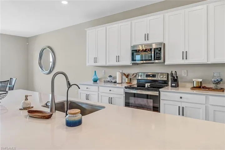 Kitchen with appliances with stainless steel finishes, white cabinetry, and sink