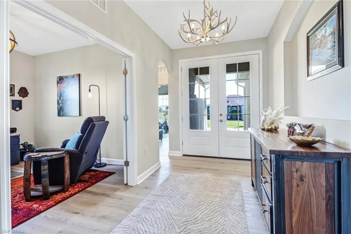 Entrance foyer featuring light hardwood / wood-style floors, a notable chandelier, and french doors