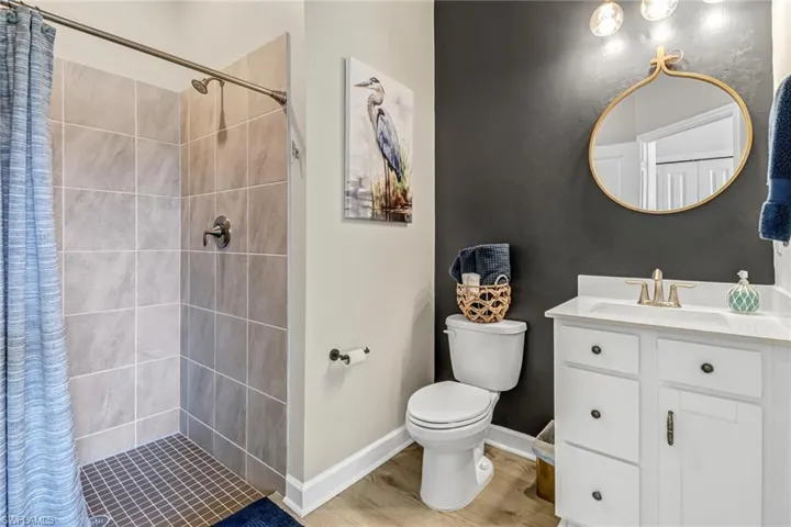Bathroom featuring walk in shower, hardwood / wood-style flooring, toilet, and vanity