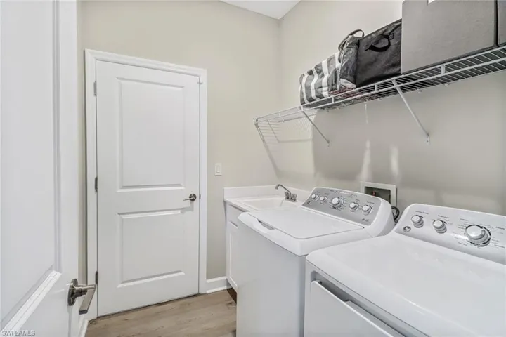 Clothes washing area featuring light hardwood / wood-style floors, sink, and independent washer and dryer