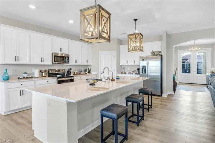 Kitchen with pendant lighting, light hardwood / wood-style flooring, appliances with stainless steel finishes, and a center island with sink