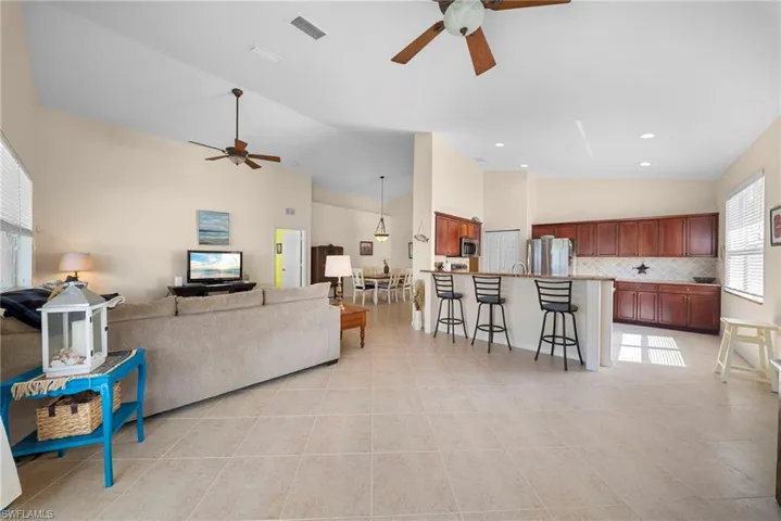 Living area featuring ceiling fan, lofted ceiling, and light tile patterned floors