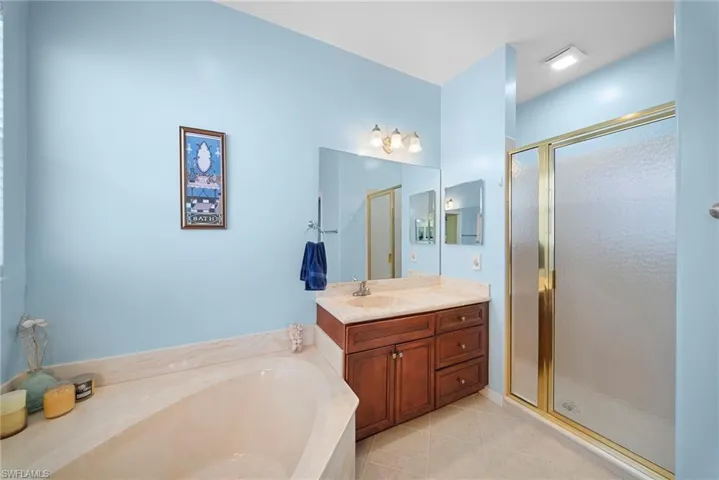 Full bathroom with a shower stall, vanity, a garden tub, and light tile patterned floors